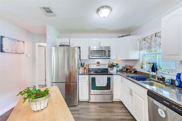 kitchen with white cabinetry, sink, stainless steel appliances, dark hardwood / wood-style flooring, and decorative backsplash