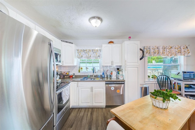 kitchen with white cabinets, decorative backsplash, sink, and stainless steel appliances