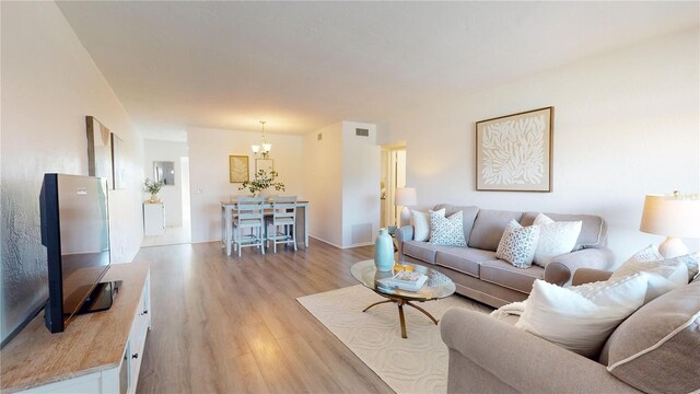 living room featuring a notable chandelier and light hardwood / wood-style flooring