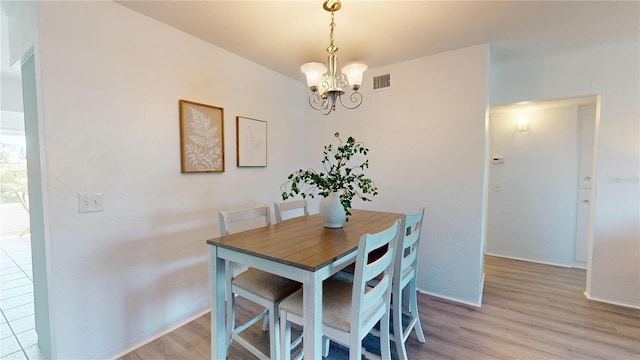 dining space with a notable chandelier and light hardwood / wood-style floors