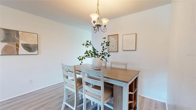 dining area with light hardwood / wood-style flooring and a notable chandelier