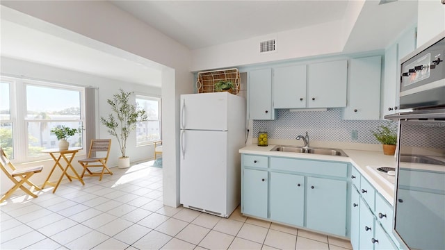 kitchen with tasteful backsplash, light tile patterned flooring, sink, and white fridge