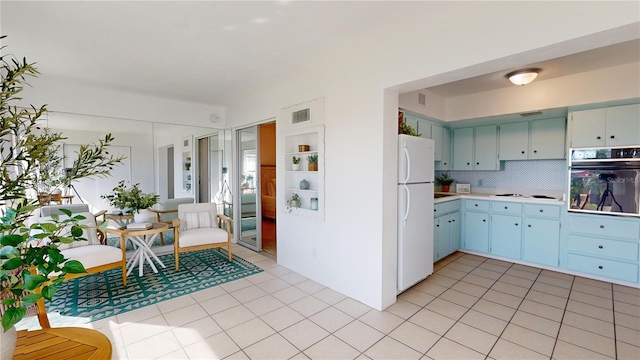 kitchen featuring light tile patterned floors, backsplash, and white appliances