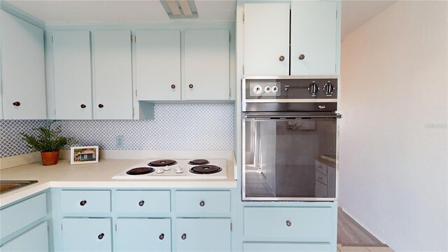 kitchen featuring decorative backsplash, white electric cooktop, oven, and white cabinetry