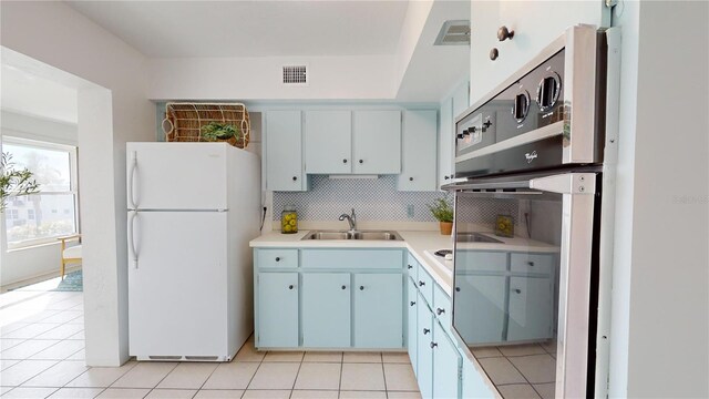 kitchen featuring tasteful backsplash, sink, light tile patterned floors, and white refrigerator