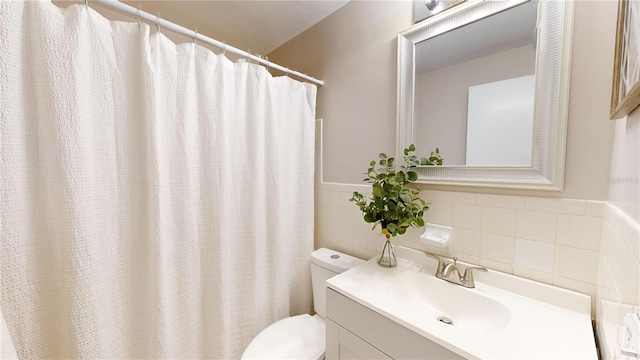 bathroom featuring vanity, toilet, and tile walls