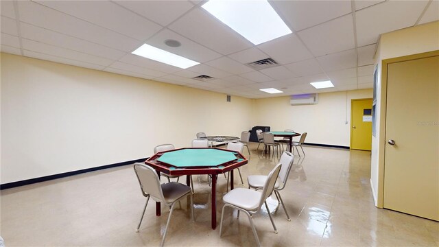 recreation room featuring a paneled ceiling and a wall mounted air conditioner