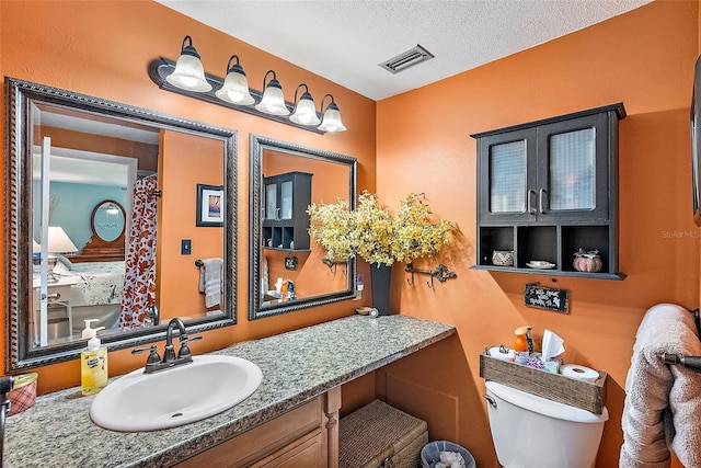 bathroom with toilet, a textured ceiling, and large vanity