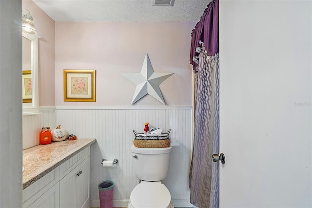 bathroom featuring a textured ceiling, oversized vanity, and toilet