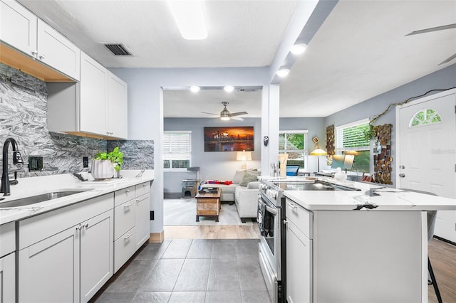 kitchen featuring white cabinetry, decorative backsplash, range with electric stovetop, and a kitchen bar