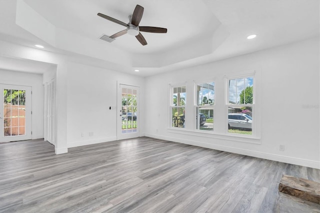 spare room featuring a tray ceiling, ceiling fan, and light hardwood / wood-style floors