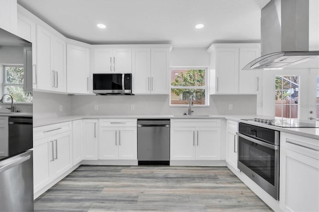 kitchen featuring sink, white cabinetry, wall chimney exhaust hood, and black appliances