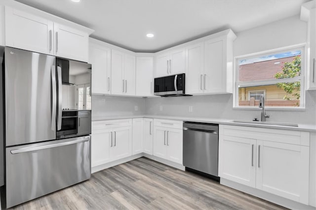 kitchen with sink, stainless steel appliances, light hardwood / wood-style flooring, backsplash, and white cabinets