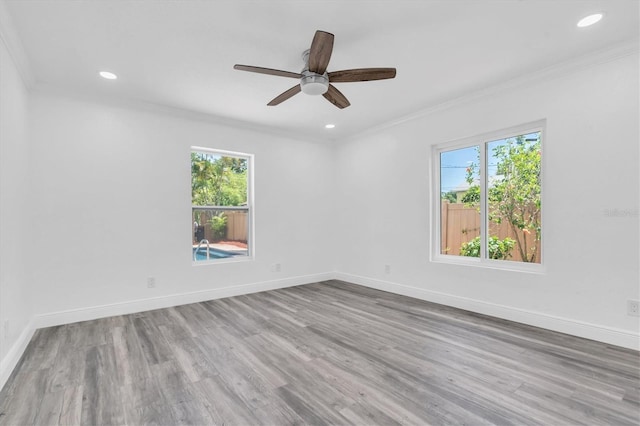 spare room with wood-type flooring, crown molding, ceiling fan, and a healthy amount of sunlight