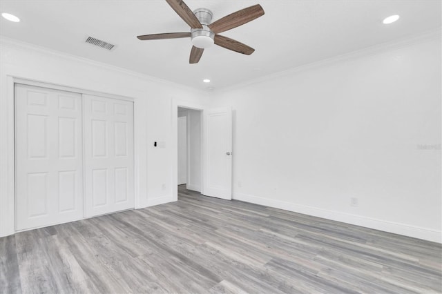 unfurnished bedroom with ceiling fan, a closet, crown molding, and light hardwood / wood-style flooring