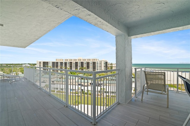 wooden deck featuring a water view and a view of the beach