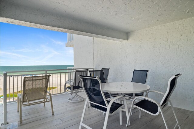 wooden terrace with a water view and a view of the beach