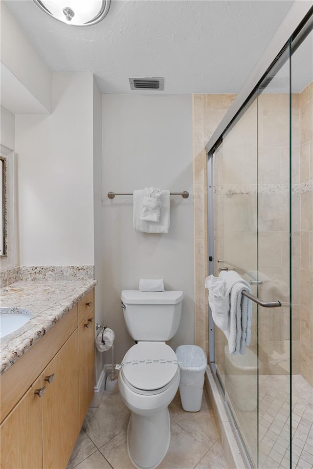 bathroom with vanity, toilet, a shower with door, and a textured ceiling