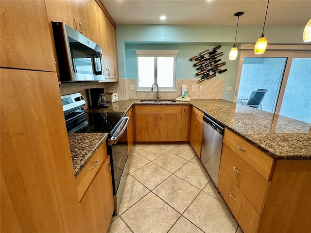 kitchen featuring appliances with stainless steel finishes, sink, dark stone countertops, hanging light fixtures, and kitchen peninsula