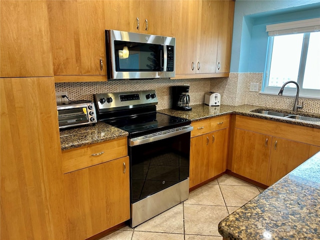 kitchen featuring stainless steel appliances, tasteful backsplash, sink, and dark stone countertops