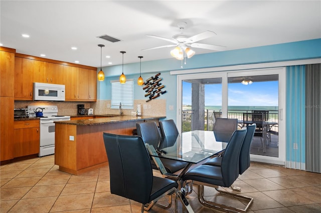 tiled dining space featuring a water view, sink, and ceiling fan