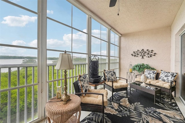 sunroom featuring ceiling fan and a water view