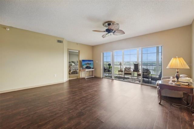 living room featuring a textured ceiling, ceiling fan, and dark wood-type flooring