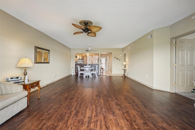 unfurnished living room featuring ceiling fan and dark wood-type flooring