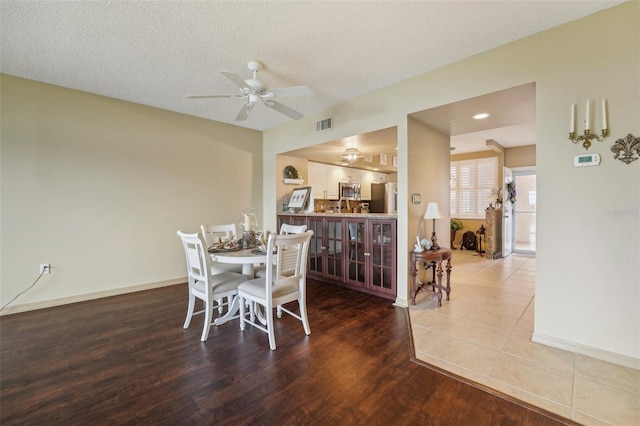 dining room with hardwood / wood-style floors, ceiling fan, and a textured ceiling