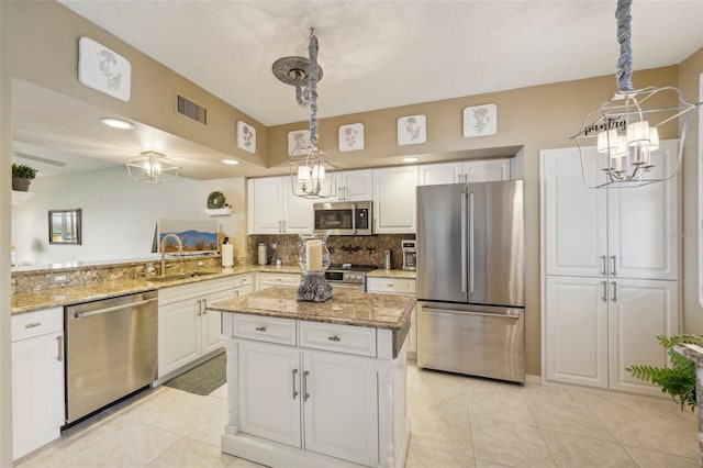 kitchen featuring kitchen peninsula, decorative light fixtures, stainless steel appliances, and white cabinetry