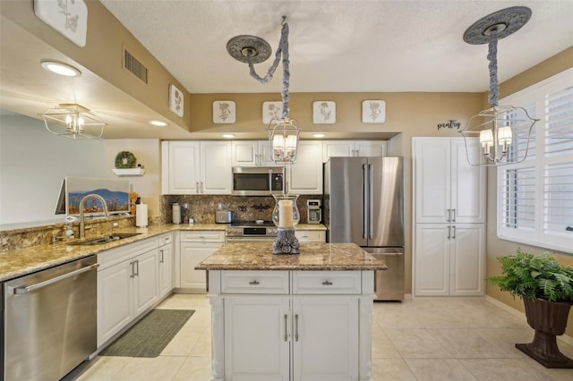 kitchen featuring pendant lighting, stainless steel appliances, white cabinetry, and sink