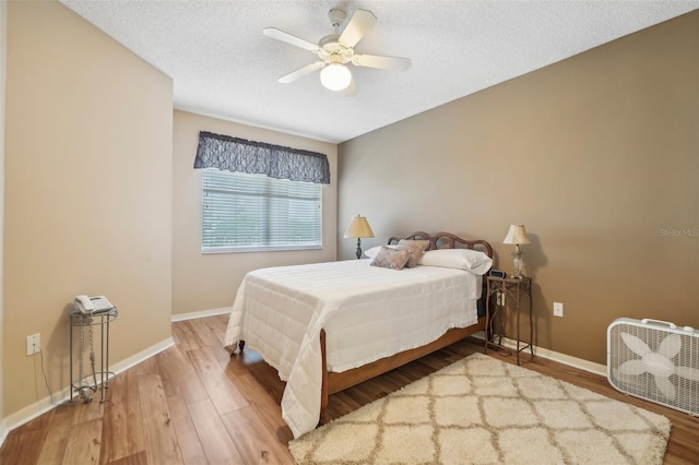 bedroom featuring hardwood / wood-style flooring, ceiling fan, and a textured ceiling