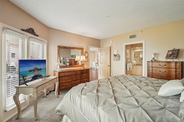 carpeted bedroom featuring ensuite bath and a textured ceiling