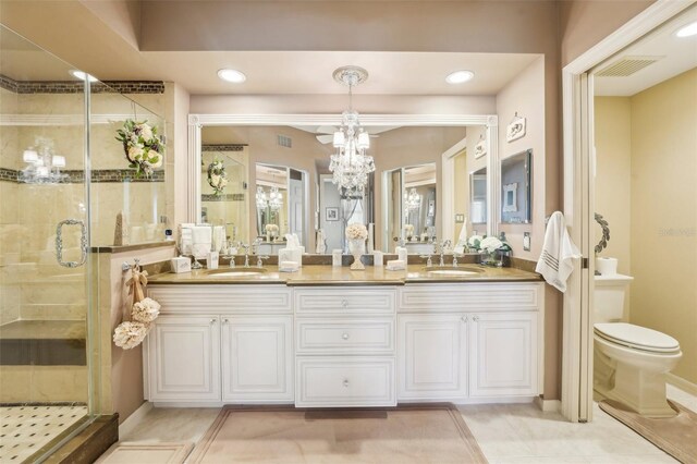 bathroom featuring tile patterned floors, vanity, toilet, and a shower with shower door