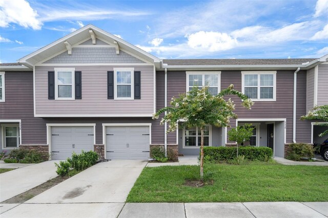 view of property featuring a garage and a front lawn