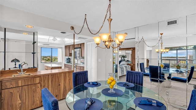 dining space with a chandelier, a textured ceiling, and sink