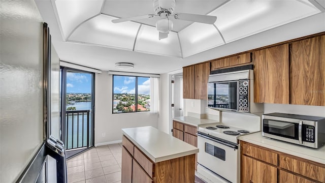 kitchen featuring ceiling fan, electric stove, a water view, a kitchen island, and fridge