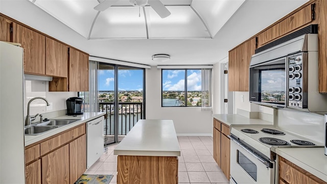 kitchen featuring light tile patterned floors, white appliances, a water view, and ceiling fan