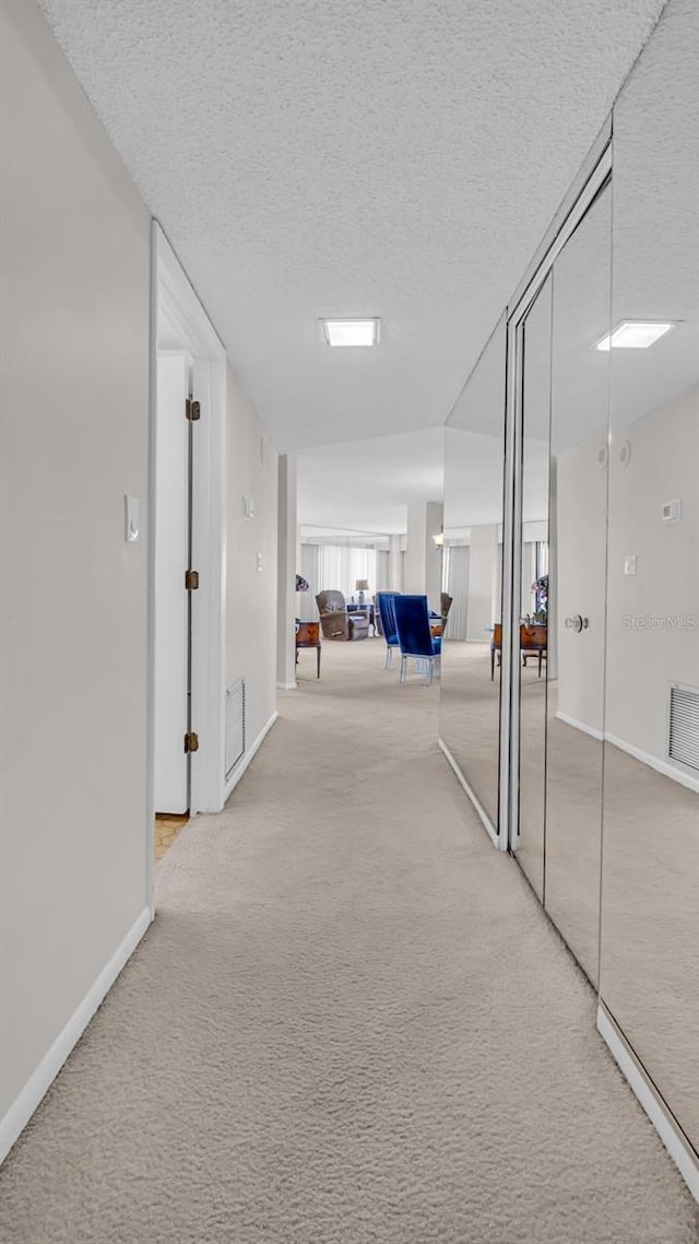 corridor with carpet flooring and a textured ceiling