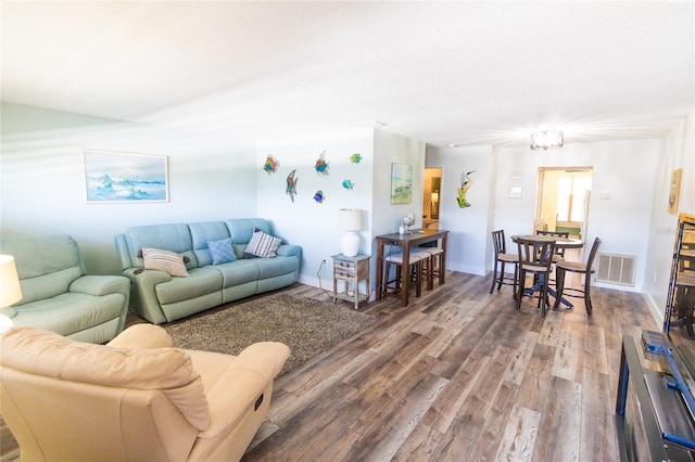 living room featuring visible vents, baseboards, and wood finished floors