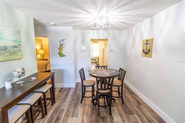 dining area featuring dark wood-style floors, baseboards, and a textured ceiling