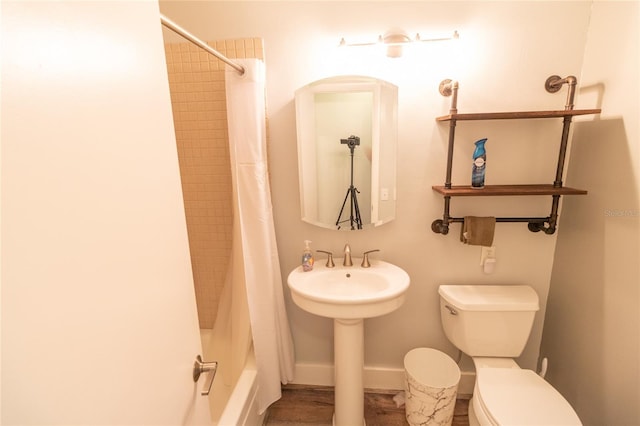 bathroom with shower / tub combo, a sink, toilet, and baseboards