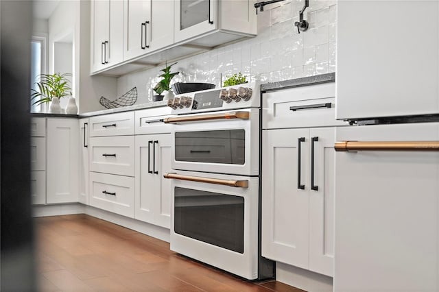 kitchen with hardwood / wood-style flooring, tasteful backsplash, double oven, and white cabinets