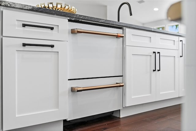 details with white cabinetry, dark wood-type flooring, and dark stone counters