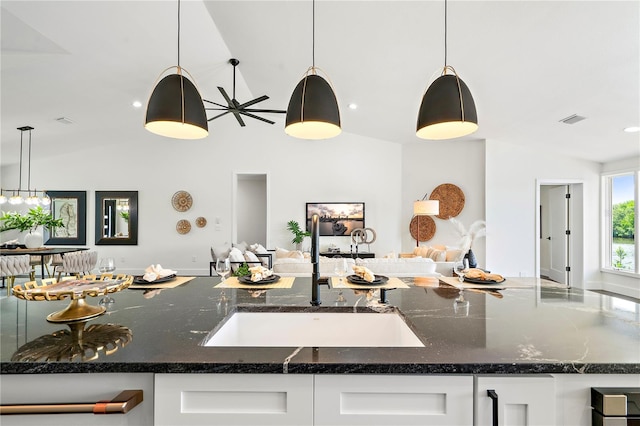 kitchen featuring lofted ceiling, white cabinets, pendant lighting, and dark stone counters