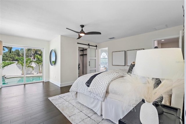 bedroom with access to outside, a barn door, a spacious closet, hardwood / wood-style floors, and ceiling fan