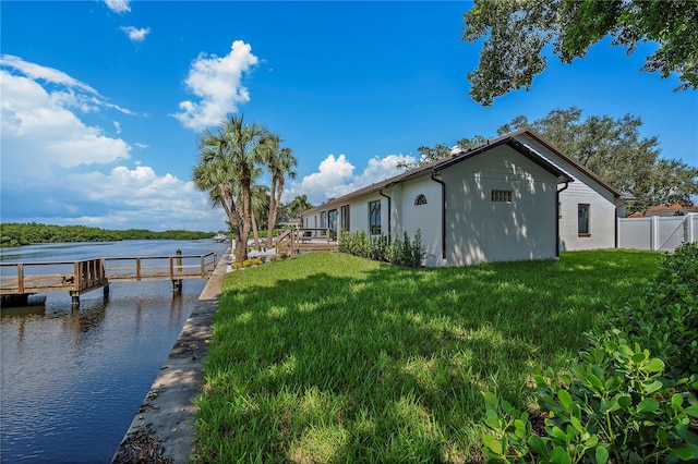 view of dock with a yard and a water view