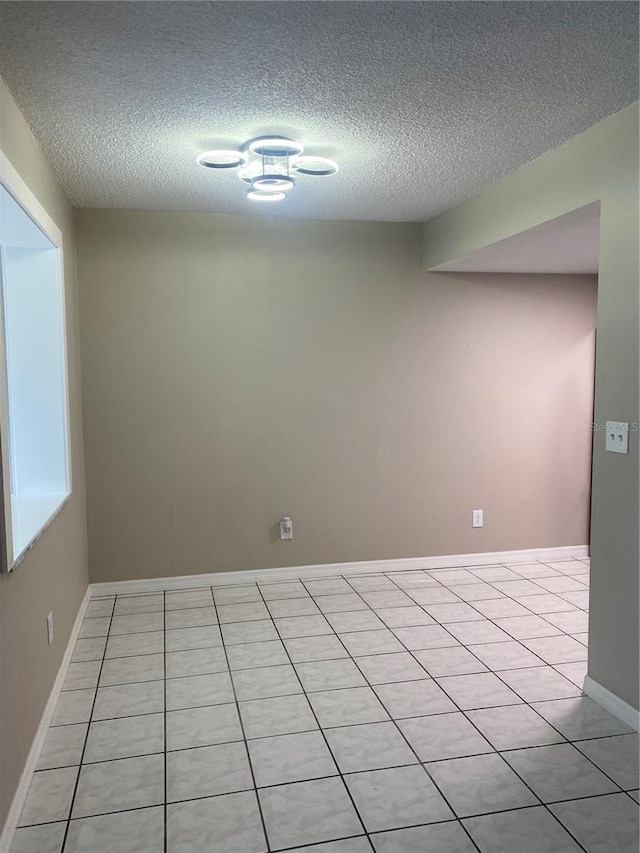 empty room with light tile patterned flooring and a textured ceiling