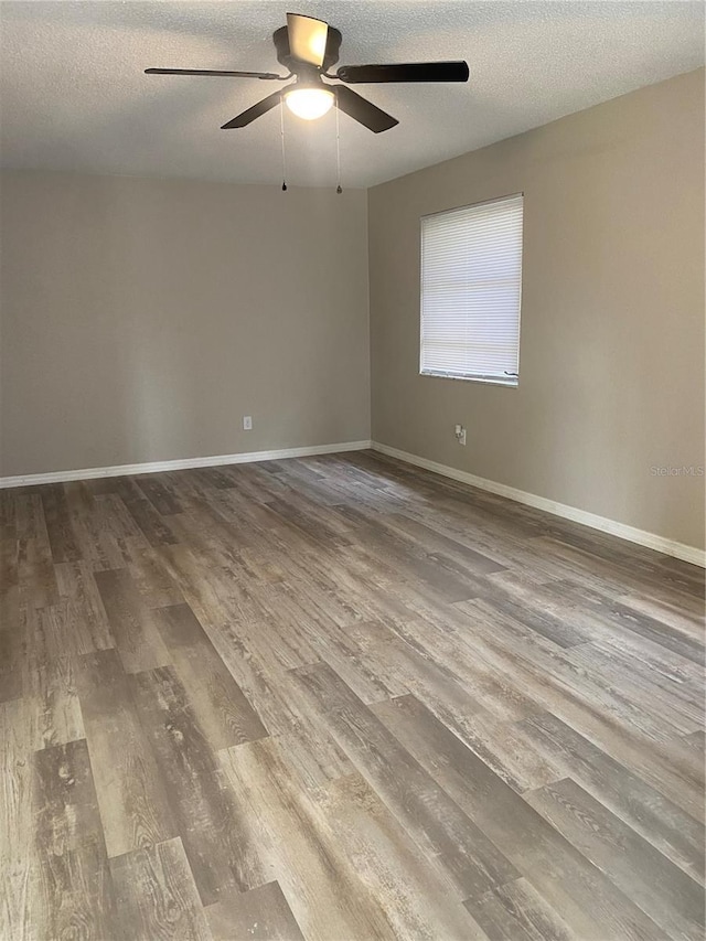 empty room with ceiling fan, wood-type flooring, and a textured ceiling