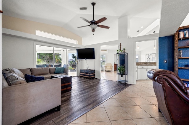 tiled living room with ceiling fan, lofted ceiling, and sink